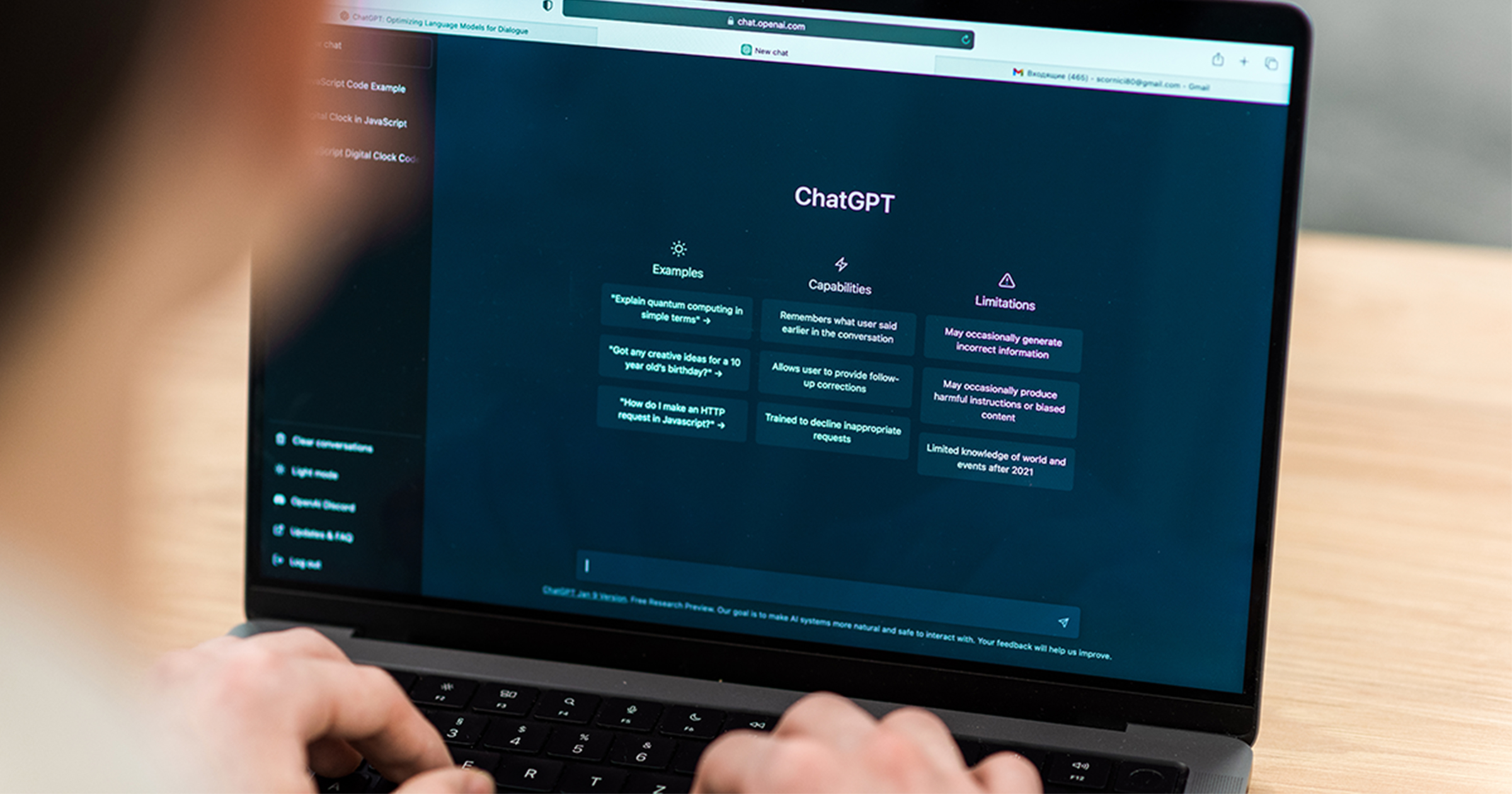 A person's hands typing on a laptop keyboard, with the ChatGPT interface visible on the screen, showing examples, capabilities, and limitations.